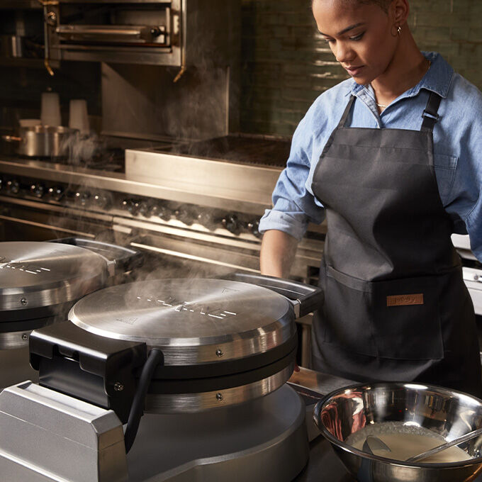 A chef stands in front of crepe makers.